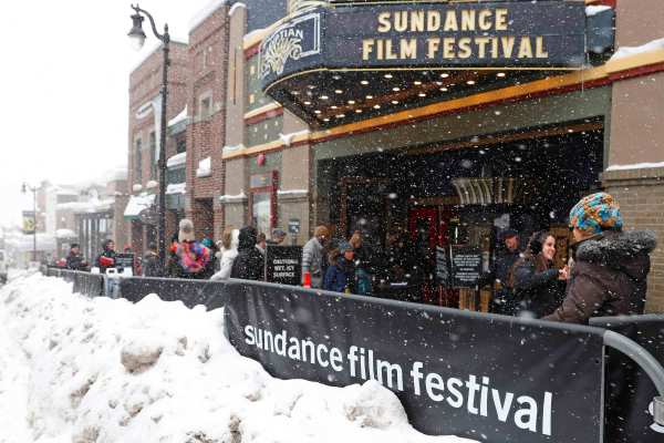 Snow piles up as people walk past the Egyptian Theater. A barricade and the theatre sign read "Sundance Film Festival."