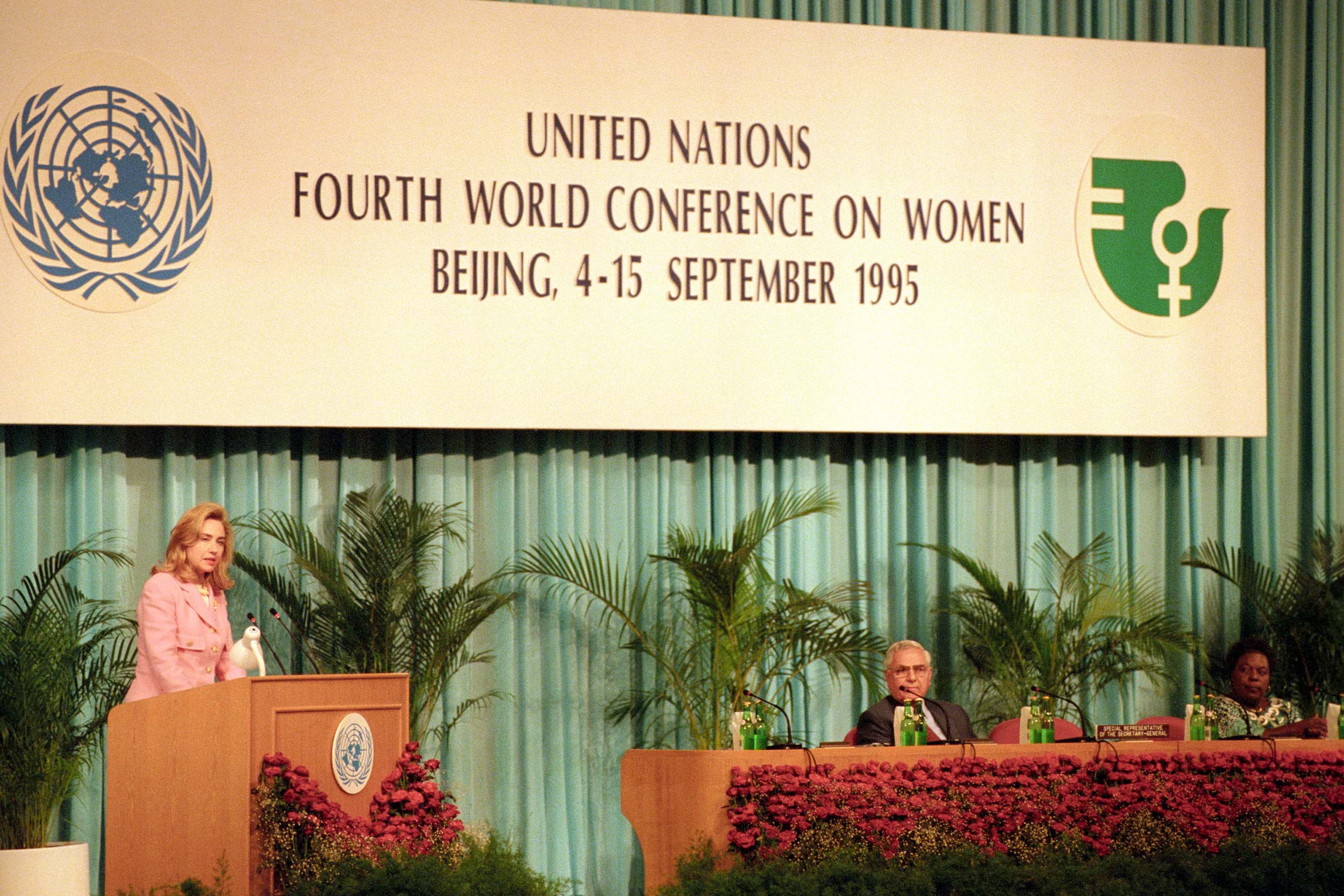 Hilary Clinton speaks on stage at a podium under a sign that reads "United Nations Fourth World Conference on Women, Beijing, 4-15 September 1995".