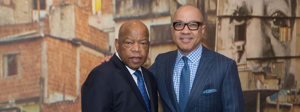 Congressman John Lewis and Ford president Darren Walker dressed in suits pose in front of a mural.
