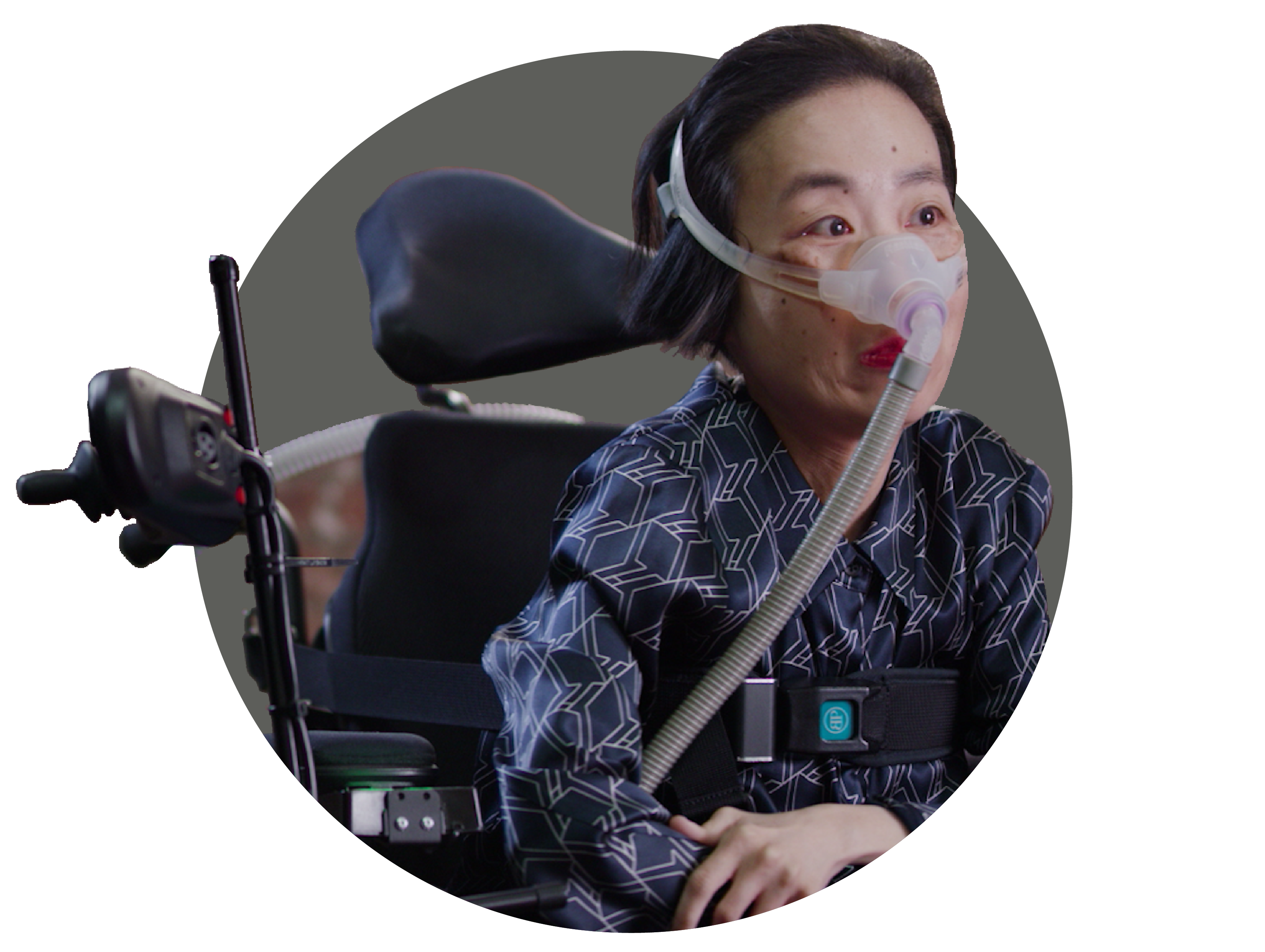 Alice Wong, an Asian American woman in a wheelchair wearing a mask over her nose attached to a tube for a BiPAP machine that helps her breathe. She is wearing a navy striped shirt and dark pants.