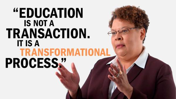 Vivian Nixon has short brown curly hair wearing wire-rimmed glasses and a burgundy blazer over a white collared blouse. She's standing next to copy that reads, "Education is not a transaction. It is a transformational process."