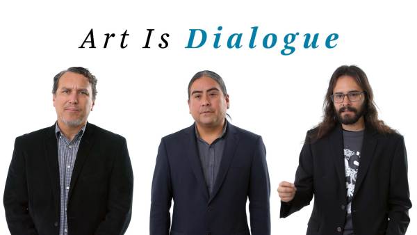 Postcommodity left to right; Kade twist wears a black blazer over a blue and white checkered button-down shirt. Raven Chacon wears a dark gray blazer over a gray button-down shirt. Cristóbal Martínez wears a black blazer over a gray crewneck t-shirt with a white graphic. The phrase "Art Is dialogue" appears above them.