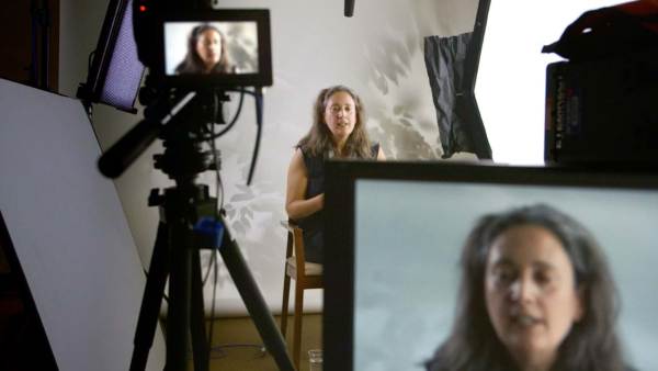 Laura Callanan sits in front of multiple cameras with her face showing on the monitor.